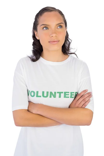 Vrouw dragen vrijwilliger tshirt met armen gekruist terwijl het zoeken naar boven — Stockfoto