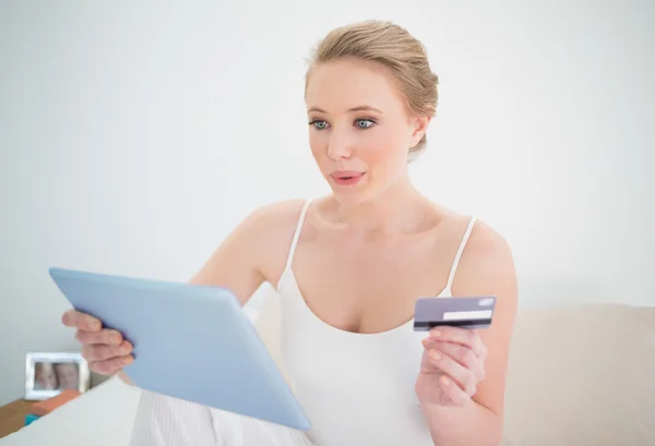 Natural happy blonde holding tablet and credit card — Stock Photo, Image