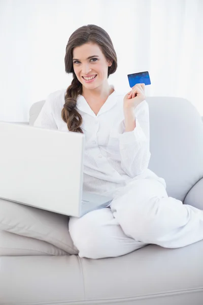 Mooie vrouw in witte pyjama's online winkelen met haar laptop — Stockfoto