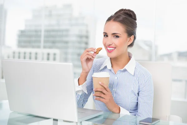 Sonriente morena empresaria sosteniendo galleta — Foto de Stock