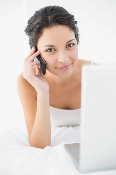 Content casual brunette in white pajamas making a phone call — Stock Photo, Image