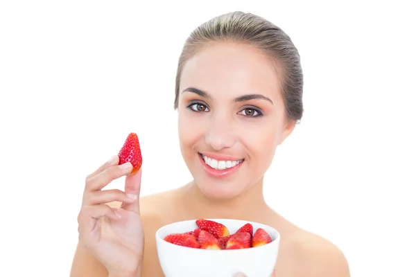 Happy young woman holding up a strawberry — Stock Photo, Image