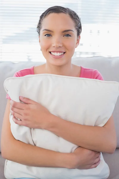 Ευτυχισμένη γυναίκα που κάθεται στον καναπέ, κρατώντας το μαξιλάρι — Φωτογραφία Αρχείου
