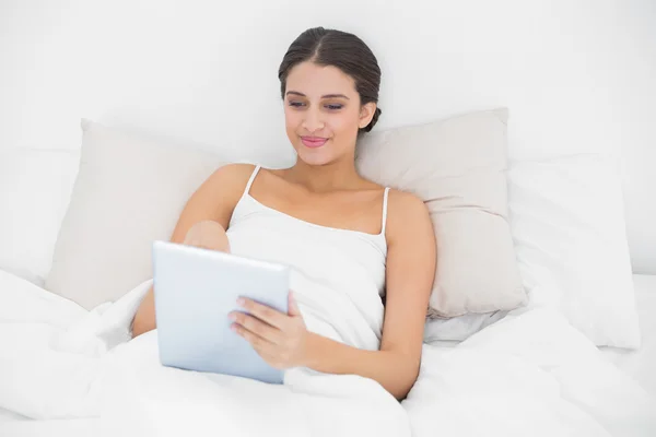 Model in witte pyjama's met behulp van een tablet pc — Stockfoto