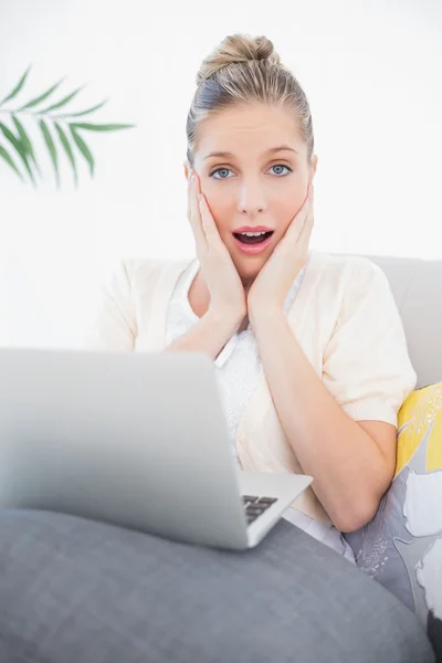 Shocked fresh model using laptop sitting on sofa — Stock Photo, Image