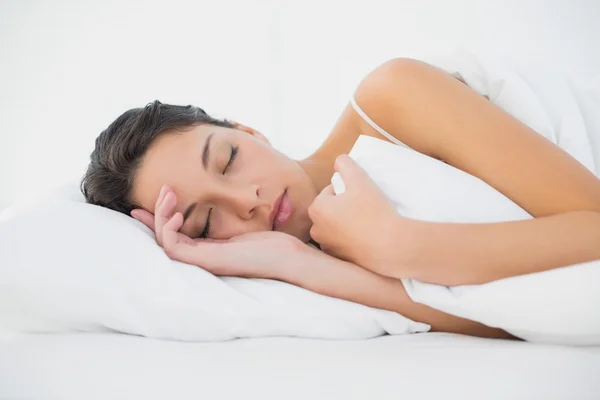 Ospalý neformální brunetka ležící v posteli — Stock fotografie