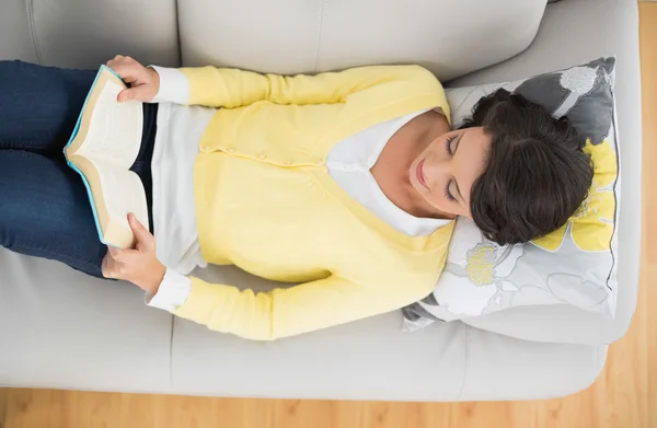 Content casual brunette in yellow cardigan reading a book — Stock Photo, Image