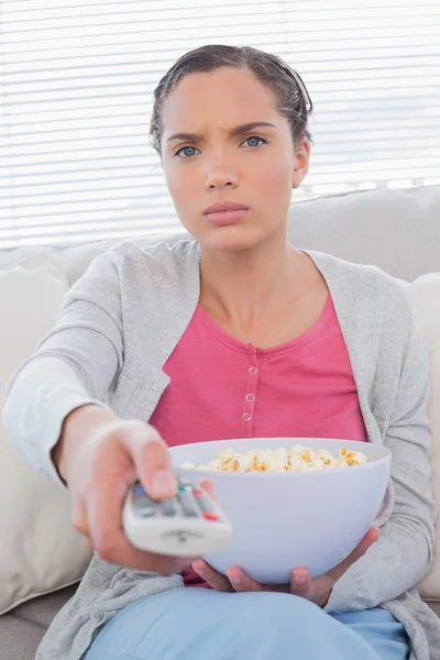 Mujer seria comiendo palomitas de maíz mientras ve la televisión — Foto de Stock