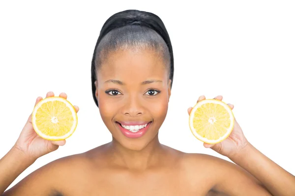 Beautiful woman holding slices of orange and looking at camera — Stock Photo, Image