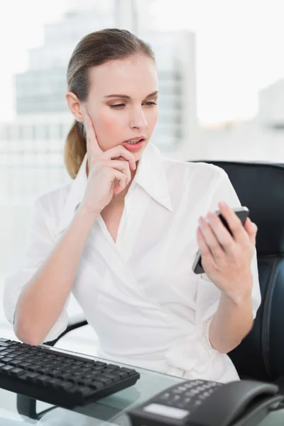 Nachdenkliche Geschäftsfrau sitzt am Schreibtisch und schickt einen Text — Stockfoto