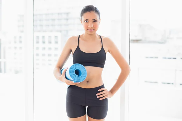 Seriomodelo en ropa deportiva que lleva una alfombra de ejercicio azul —  Fotos de Stock