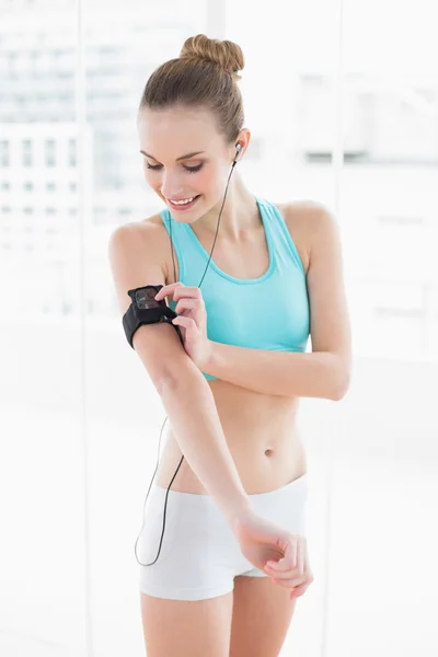 Sporty happy woman pressing a button on mp3 player — Stockfoto