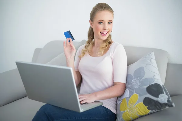 Випадкова щаслива блондинка тримає ноутбук і кредитну картку — стокове фото