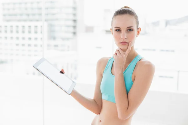 Sporty pensive woman holding a tablet — Stock Photo, Image