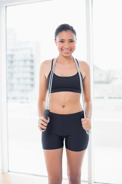 Content dark haired model in sportswear holding a skipping rope — Stock Photo, Image