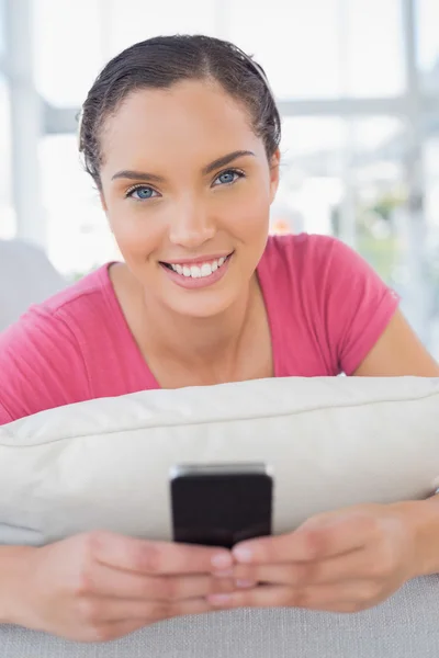 Attraktive Frau, die auf dem Sofa liegt und SMS schreibt — Stockfoto