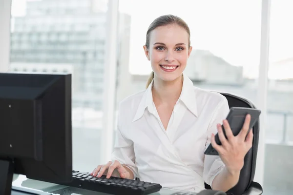 Gelukkig zakenvrouw bedrijf rekenmachine zit aan Bureau — Stockfoto