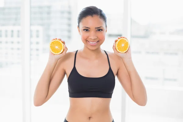 Beautiful model in sportswear holding orange halves — Stock Photo, Image