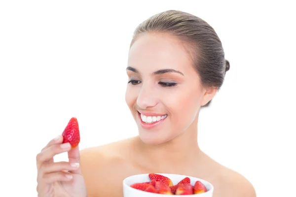 Young woman smiling at a strawberry — Stock Photo, Image