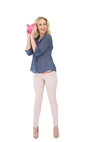Curious pretty blonde holding piggy bank — Stock Photo, Image