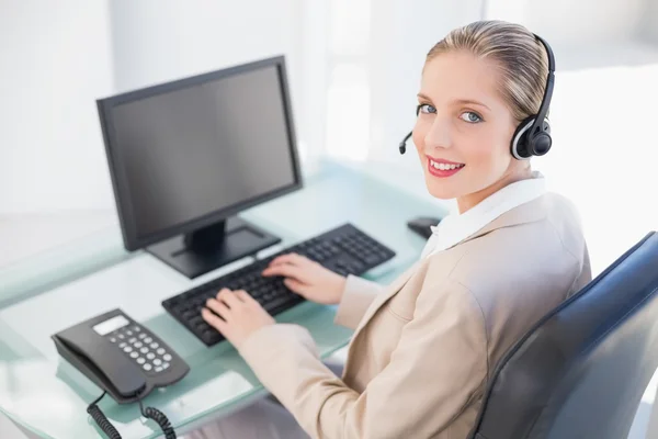 Lächelnde blonde Callcenter-Agentin tippt — Stockfoto