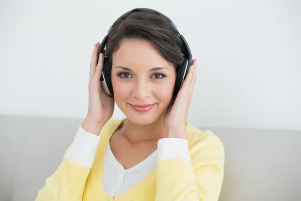 Content casual brunette in yellow cardigan listening to music with headphones — Stock Photo, Image