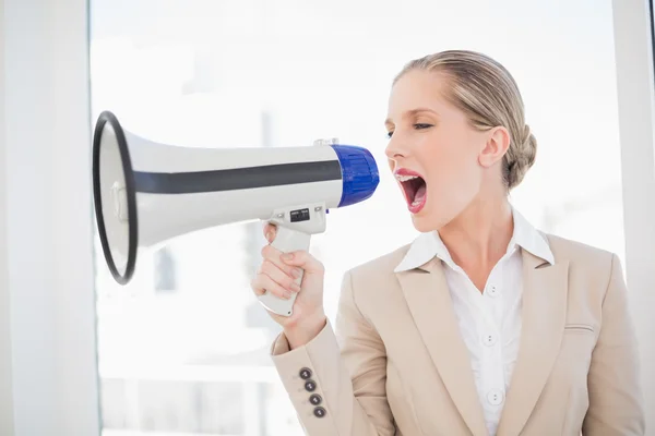 Serious blonde businesswoman screaming in megaphone — Stock Photo, Image