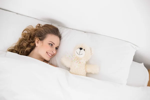 Sonriente morena acostada junto al osito de peluche — Foto de Stock