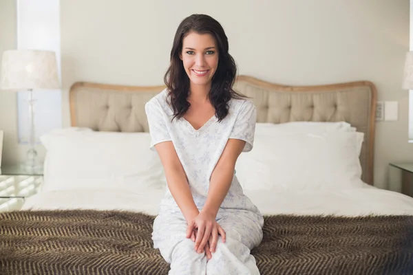 Yatağı üzerinde oturan memnun güzel kadın — Stok fotoğraf