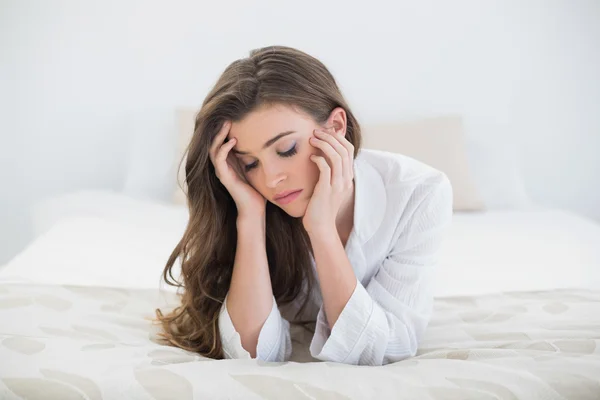 Mujer triste en pijama blanco acostada en su cama — Foto de Stock