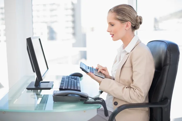 Zijaanzicht van vrolijke blonde zakenvrouw met behulp van calculator — Stockfoto