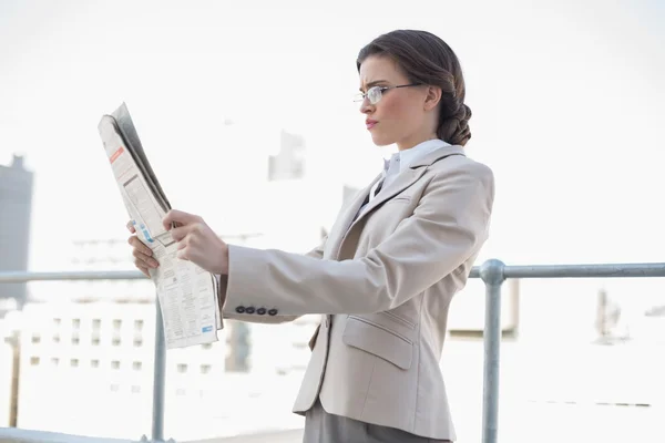 Serious stylish businesswoman reading a newspaper — Stock Photo, Image