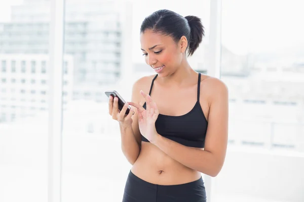 Koncentrerad modell i sportkläder att skriva på en mobiltelefon — Stockfoto