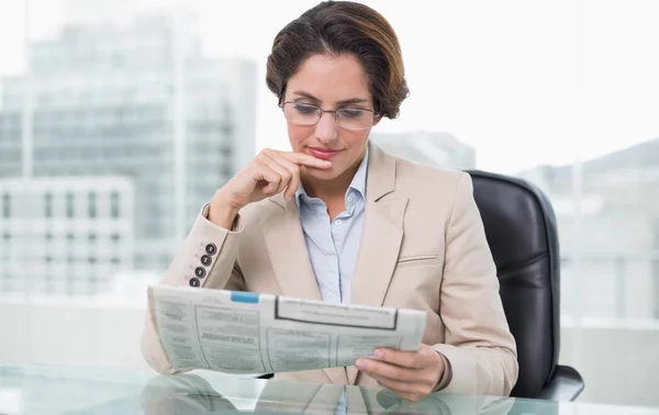 Businesswoman reading newspaper at her desk — Stock Photo, Image