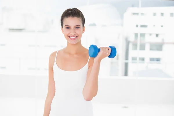 Mulher de sportswear branco levantando um halteres — Fotografia de Stock