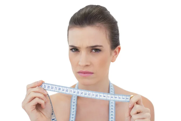 Frowning model holding a measuring tape — Stock Photo, Image