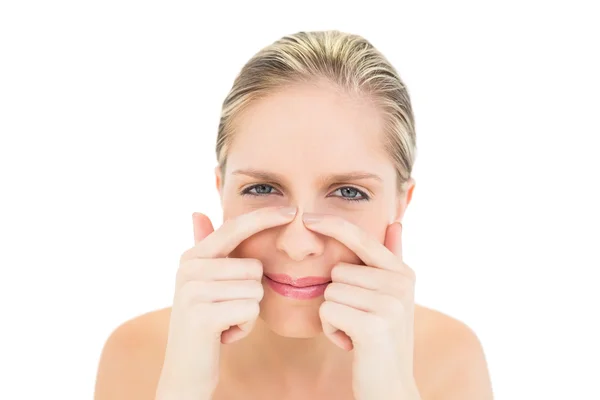 Frowning fresh blonde woman pressing her nose — Stock Photo, Image