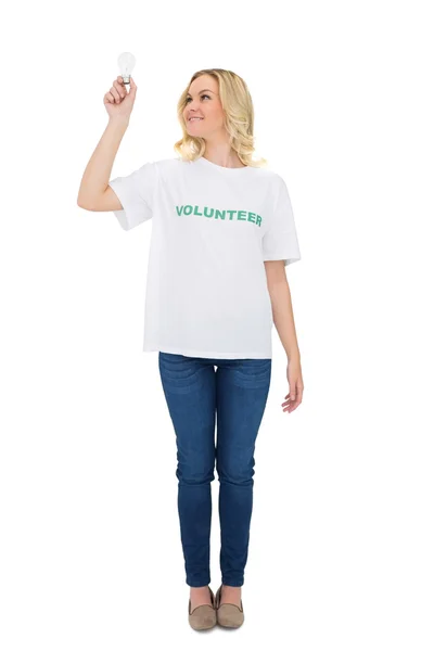 Улыбающаяся блондинка-волонтер держит лампочку — стоковое фото