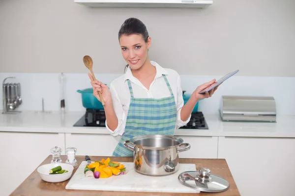 Frau trägt Schürze mit Tablet beim Kochen — Stockfoto
