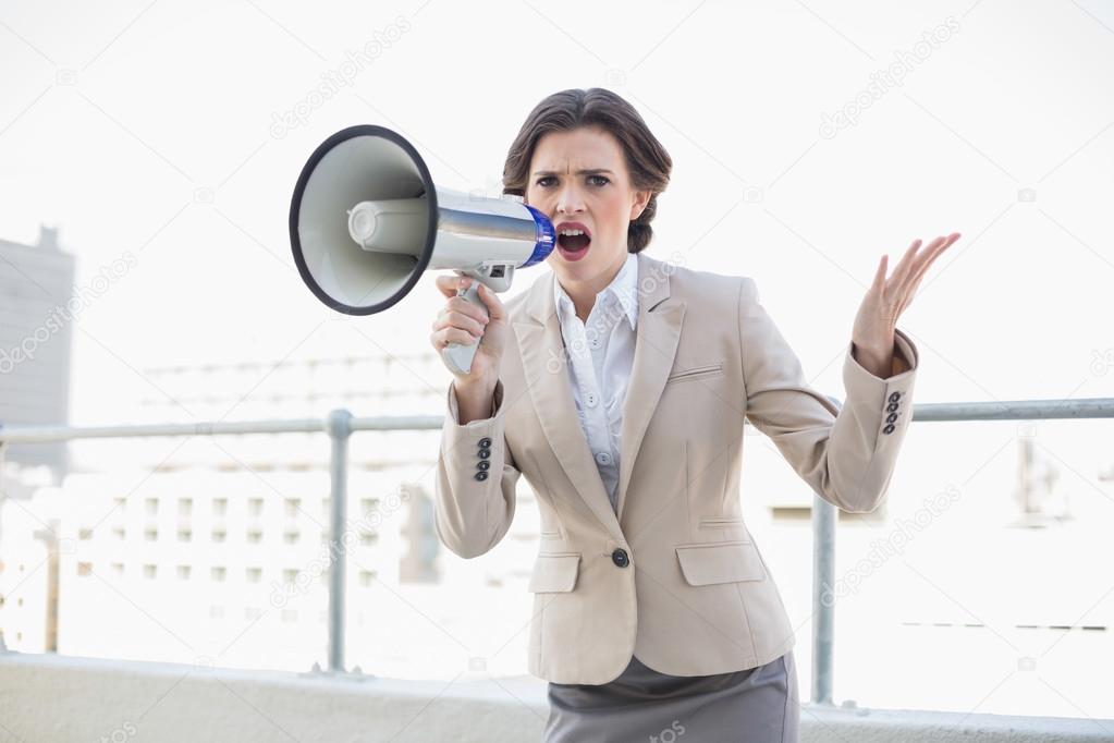 Unhappy stylish businesswoman screaming in a megaphone