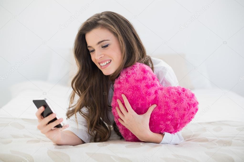 Content woman in white pajamas using her mobile phone
