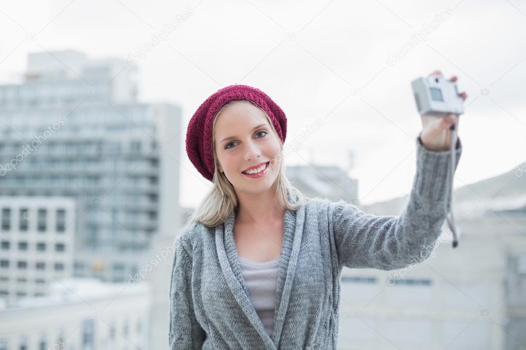 Smiling pretty blonde taking a self picture outdoors