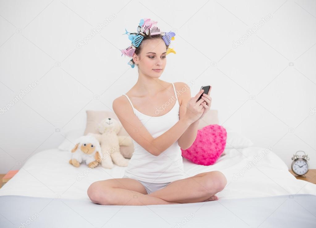 Stern woman in hair curlers using her mobile phone