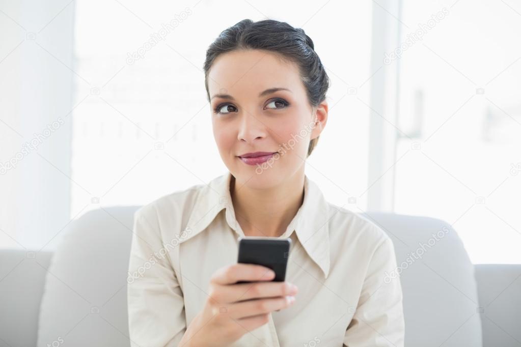Dreamy stylish brunette businesswoman using her mobile phone