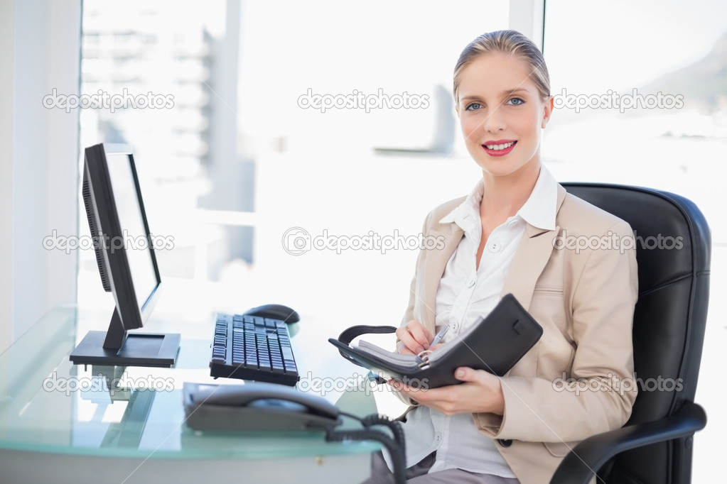 Happy blonde businesswoman holding datebook