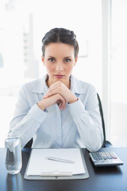 Ellerini katılma ve kameraya bakarak gülmeyen şık esmer işkadını