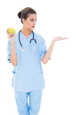 Yeşil elma tutan mavi güzel hemşire scrubs