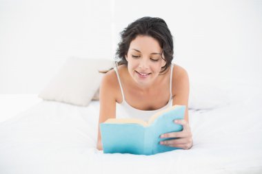 büyüleyici casual esmer beyaz kitap okumak onun yatakta yatarken pijama