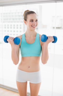 dumbell holding ve uzağa bakarak sportif neşeli kadın