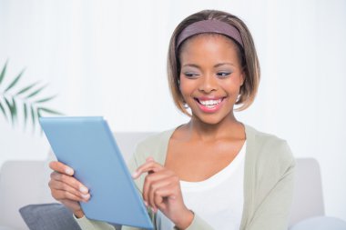 mutlu bir kadın onun tablet kullanarak koltukta oturan